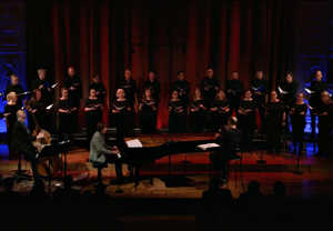 Man playing piano with a large choir behind. From the movie.