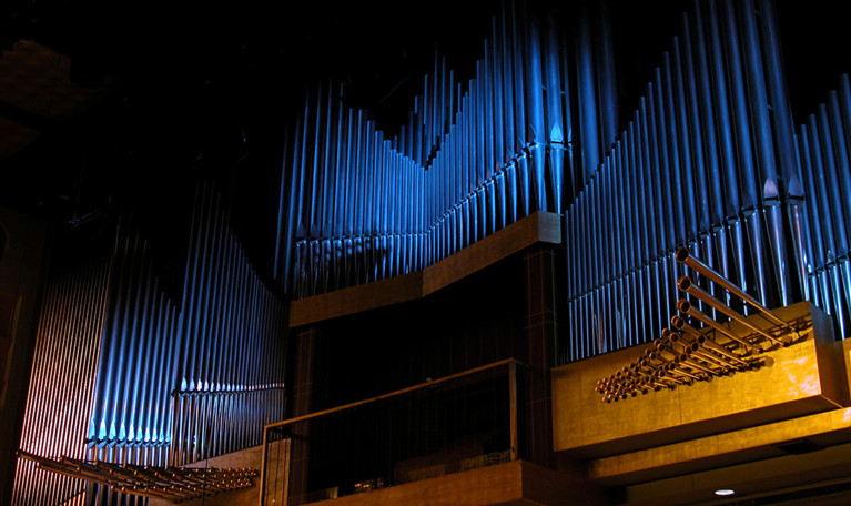 Metal pipes protrude from the front of the organ. Photography.