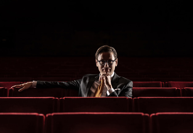 Man som sitter bland fåtöljer. Fotografi