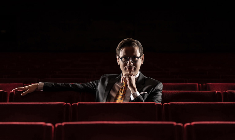 Man som sitter bland fåtöljer. Fotografi. 