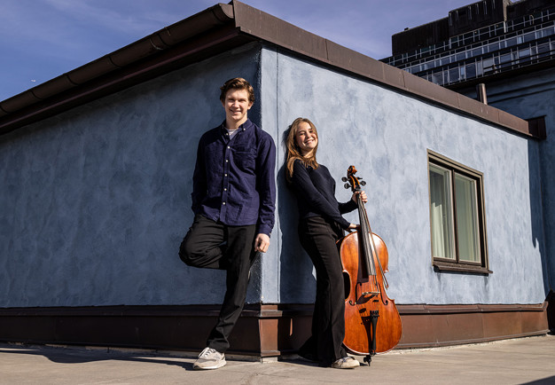 Two musicians leaning against a wall. Photo.